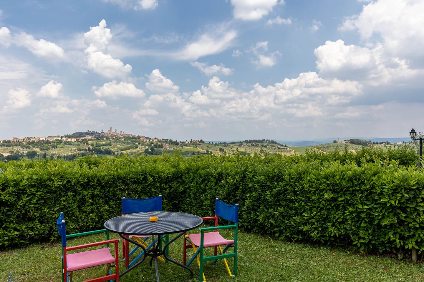 A view of a town from a grassy area with a table and chairs.