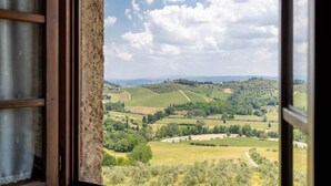 A view from a window overlooking a rural landscape with rolling hills and vineyards. - Agriturismo Il Casolare di Bucciano (San Gimignano)