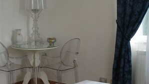 A hotel room with a bed, a table with chairs, a lamp, and a window with curtains. - La Rotella nel Sacco (Rome)