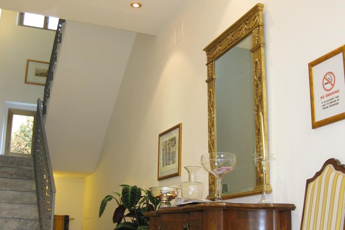 A staircase with a marble finish, a wooden dresser with a mirror, a chair with striped upholstery, and a 'No Smoking' sign on the wall.