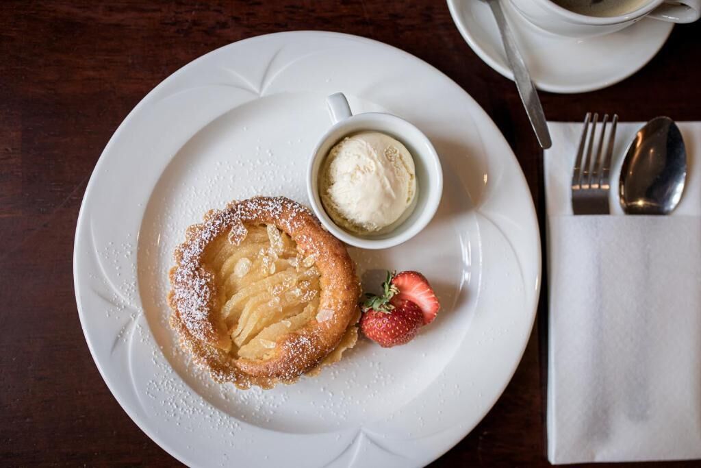 A plate with a dessert, a cup of coffee, and a strawberry on a table.