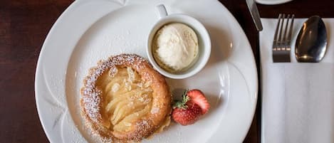A plate with a dessert, a cup of coffee, and a strawberry on a table.