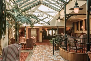 A hotel lobby with a high ceiling, a central staircase, and a seating area with chairs and tables. - Kee's Hotel  (Stranorlar)