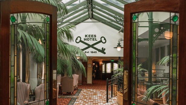 Un vestíbulo de hotel con piso a cuadros, sillas a rayas y un letrero que dice "KEES HOTEL Est 1845".