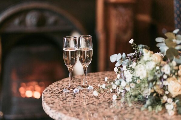Two glasses of champagne on a round table with a floral arrangement beside them. - Kee's Hotel  (Stranorlar)