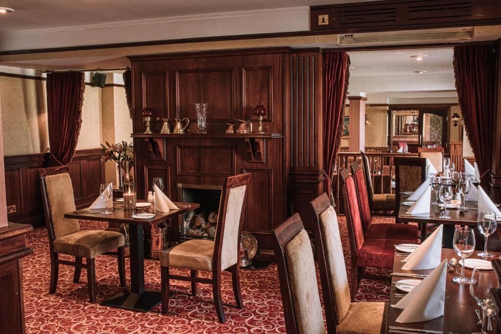 Un comedor con paneles de madera, cortinas rojas y una alfombra estampada.