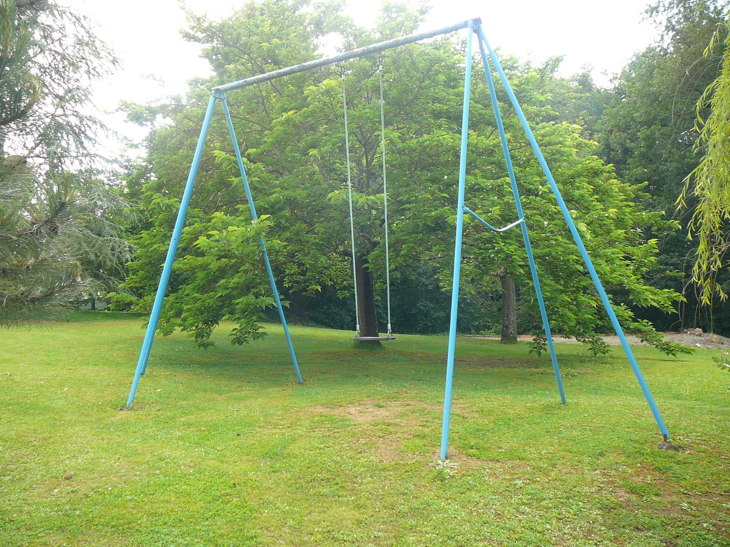 A swing set in a grassy area with trees in the background.