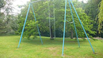 A swing set in a grassy area with trees in the background.