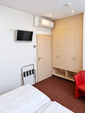 A hotel room with a bed, a TV, a wardrobe, and a red chair. - HRC Pfeffermühle (Landstuhl)