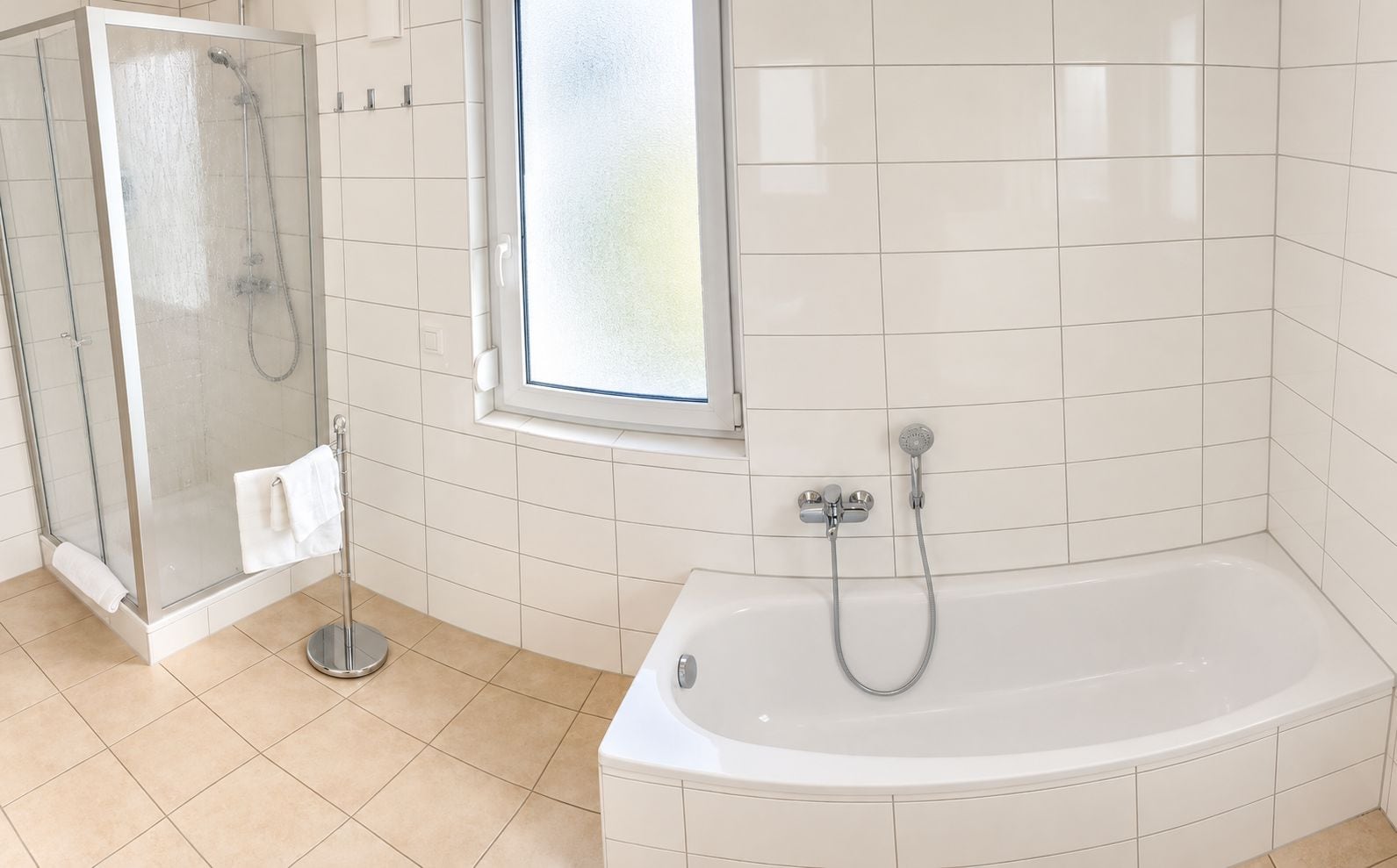 Un baño con ducha envuelta en vidrio, una bañera y un ventanal.