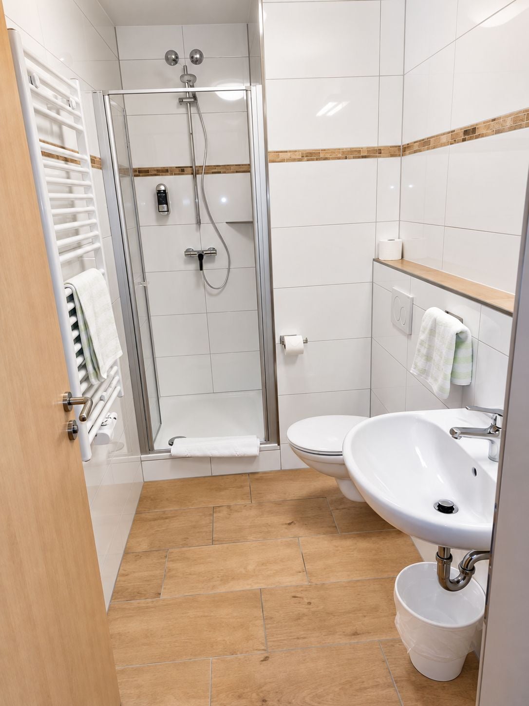Un baño moderno con ducha envuelta en vidrio, un lavamanos blanco y un inodoro.