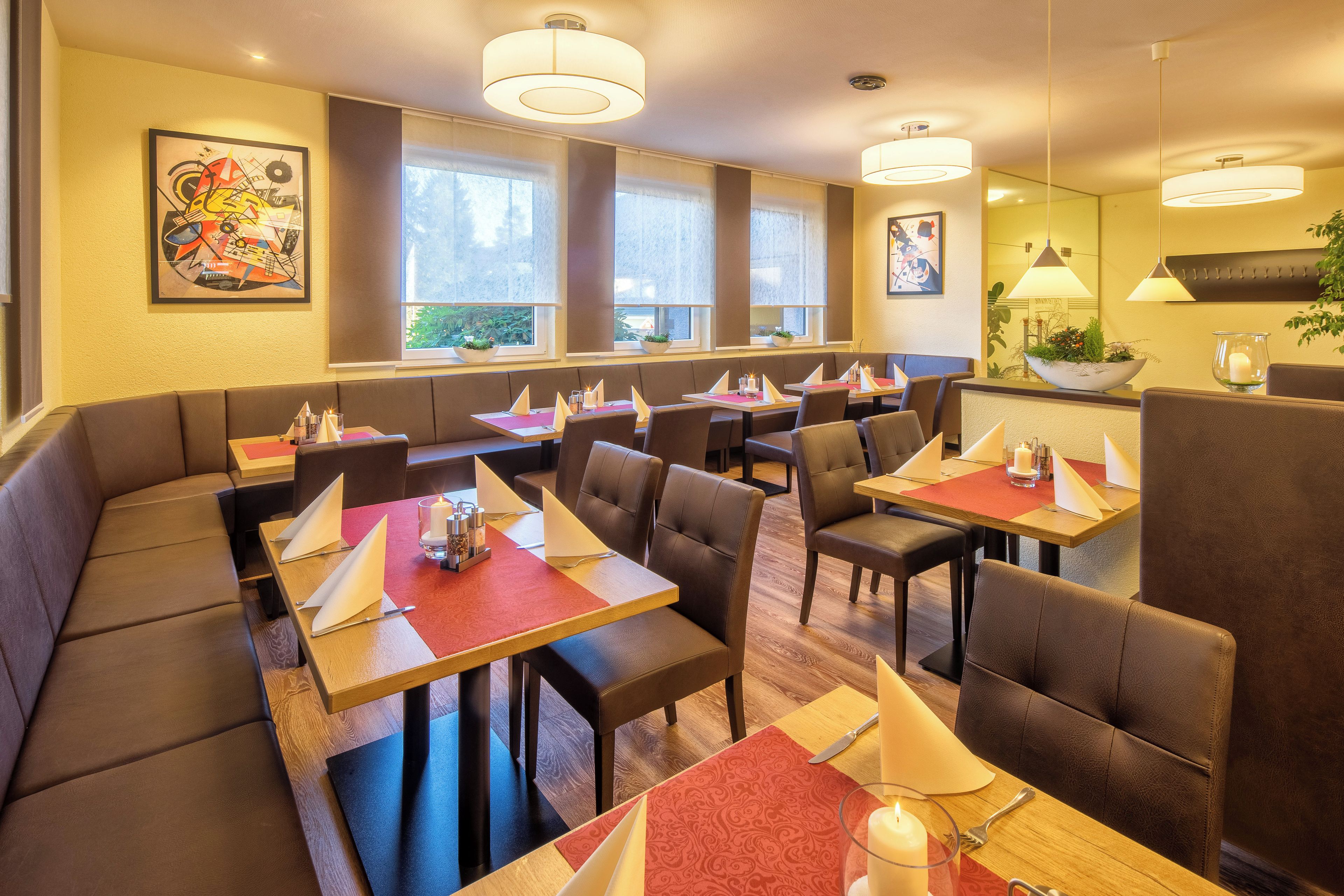 A restaurant with booths and tables, large windows, and artwork on the walls.