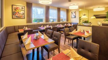 A restaurant with booths and tables, large windows, and artwork on the walls.