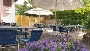 An outdoor cafe with tables and chairs, surrounded by a garden with purple flowers. - HRC Pfeffermühle (Landstuhl)