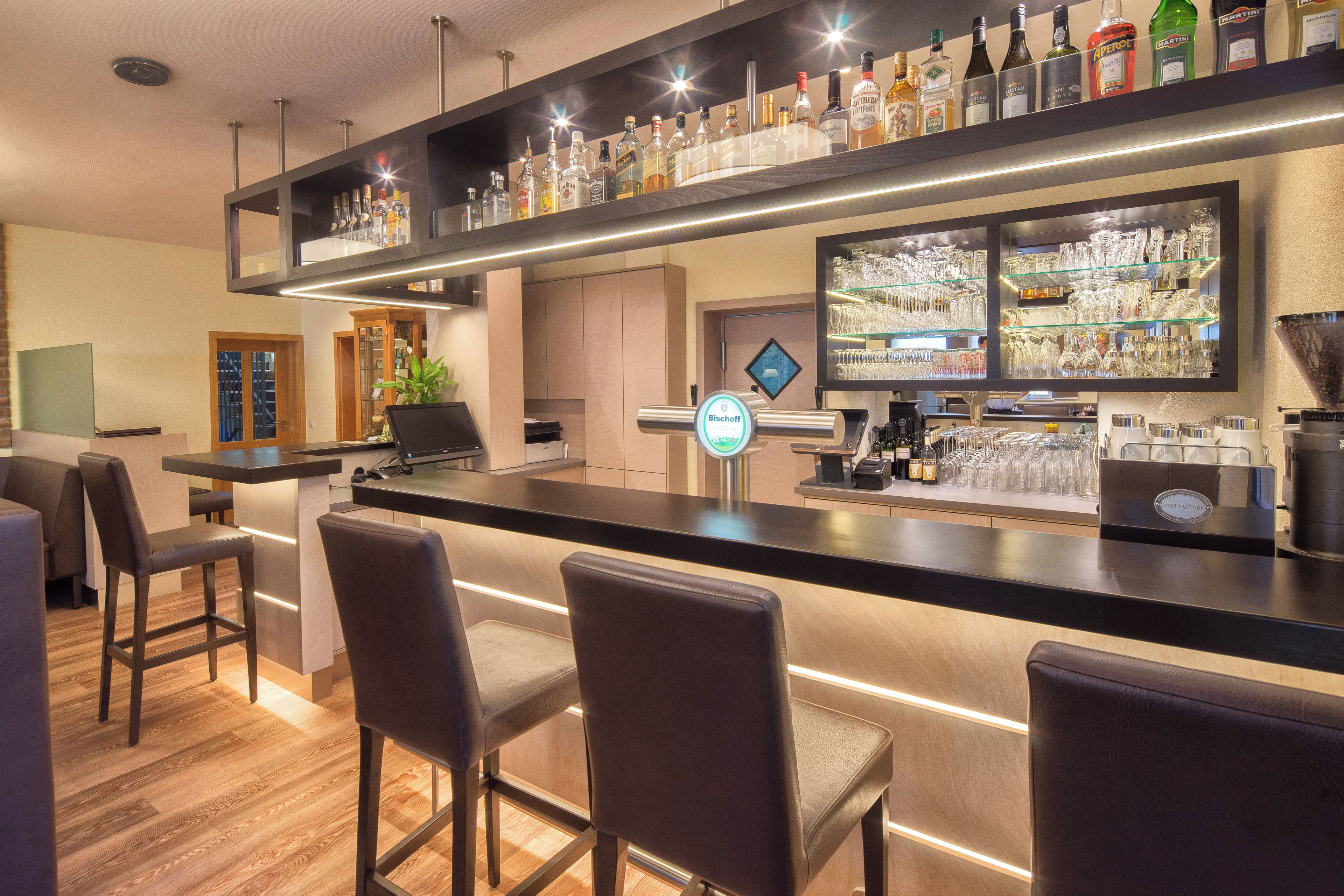 A bar area with a counter, stools, and a variety of liquor bottles.