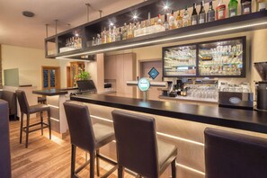 A bar area with a counter, stools, and a variety of liquor bottles. - HRC Pfeffermühle (Landstuhl)