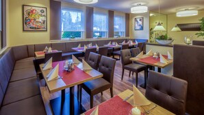 A restaurant with booths and tables, large windows, and artwork on the walls. - HRC Pfeffermühle (Landstuhl)