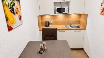 Eine kleine Küche mit Mikrowelle, Wasserkocher und einer Holz Arbeitsplatte.