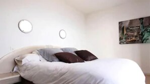 A bedroom with a bed, pillows, and a wall-mounted artwork. - Résidence Roc e Mare (Cargese)