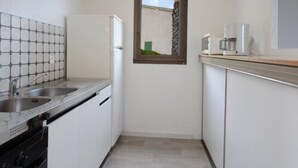 A compact kitchen with a double sink, a refrigerator, and a coffee maker on the countertop. - Résidence Roc e Mare (Cargese)