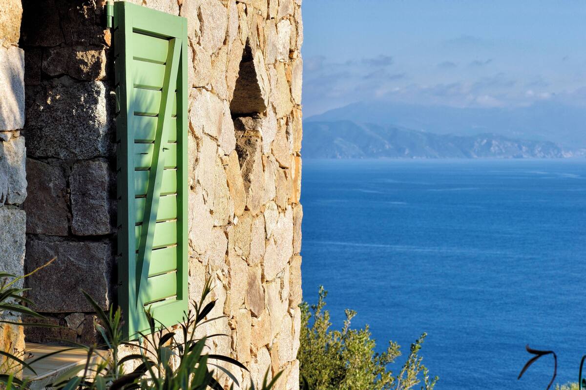 Un edificio de piedra con una puerta verde y vistas al mar.