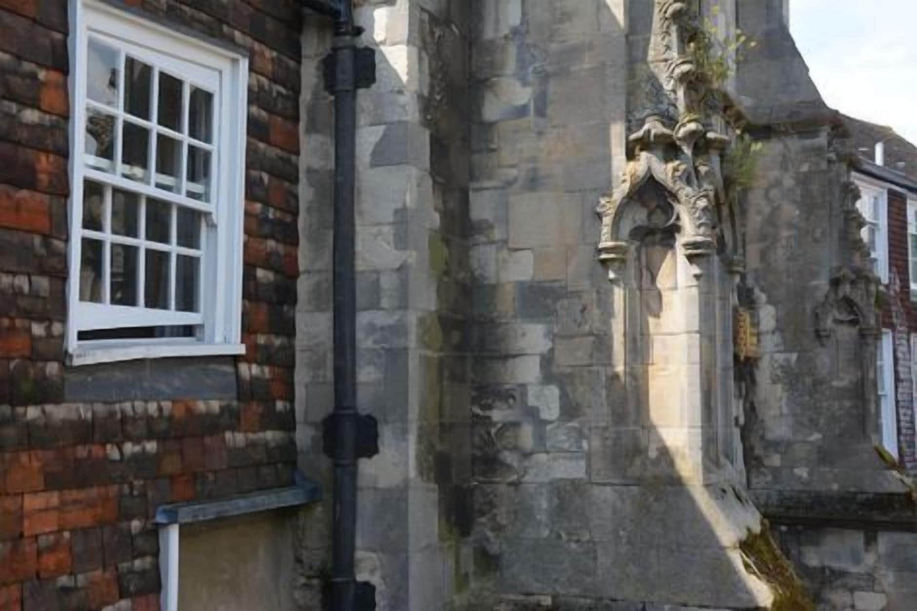 A stone building with a window and a black pipe.