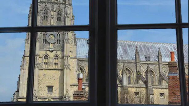 Un bâtiment historique à l’architecture gothique, caractérisé par des arcs brisés et une tour horloge.