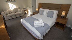 Une chambre d’hôtel avec un grand lit, un canapé, une table de chevet et une lampe.