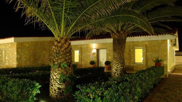 A stone building with a tiled roof, surrounded by well-maintained hedges and palm trees. - Il Galeone Bed and Breakfast (Taranto)