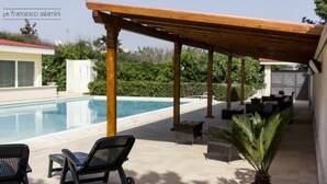 A covered outdoor area with a pool, lounge chairs, and potted plants. - Il Galeone Bed and Breakfast (Taranto)