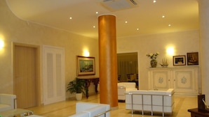 A spacious lobby with white sofas, a large pillar, and a decorative cabinet. - Il Galeone Bed and Breakfast (Taranto)