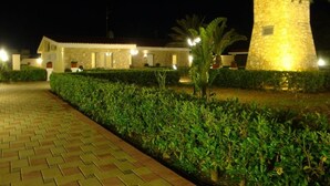 A well-lit pathway leading to a stone building with a large tree nearby. - Il Galeone Bed and Breakfast (Taranto)
