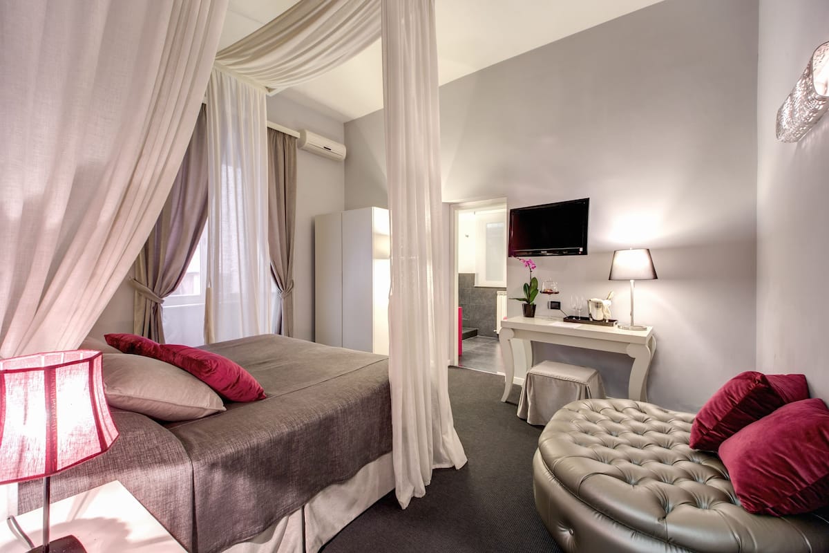 A hotel room with a bed, a desk, a TV, and a chair.