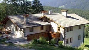 Une maison à deux étages, dotée d’un toit en pente, d’un balcon en bois et d’une cheminée.