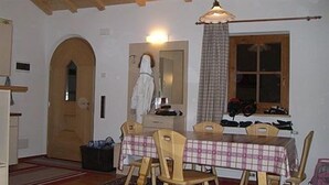 Un coin repas avec une table recouverte d’une nappe à carreaux, entourée de chaises en bois.