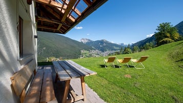 A wooden deck with a table and chairs overlooking a mountainous landscape.
