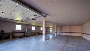 Un vaste espace intérieur inachevé, doté d’un sol en béton, de piliers blancs et d’un haut plafond laissant apparaître les conduits.