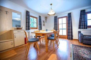 Un comedor con mesa y sillas de madera, una cocina con armarios, y un sofá en una sala de estar.