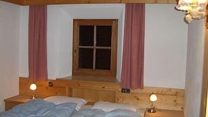 Une pièce confortable avec un lit en bois, deux lampes de chevet et une fenêtre avec des rideaux.
