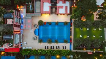 Vista aérea de un hotel con piscina, mobiliario exterior y un jardín cuidado.