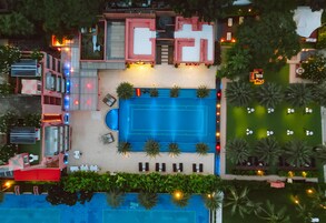 Vista aérea de un hotel con piscina, mobiliario exterior y un jardín cuidado.
