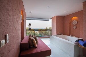 Un ba ño moderno con una bañera grande, un banco con cojines y un balcón con vistas.