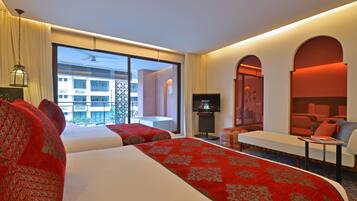 Habitación de hotel con dos camas, televisión, sofá y una ventana grande con vistas a edificios.