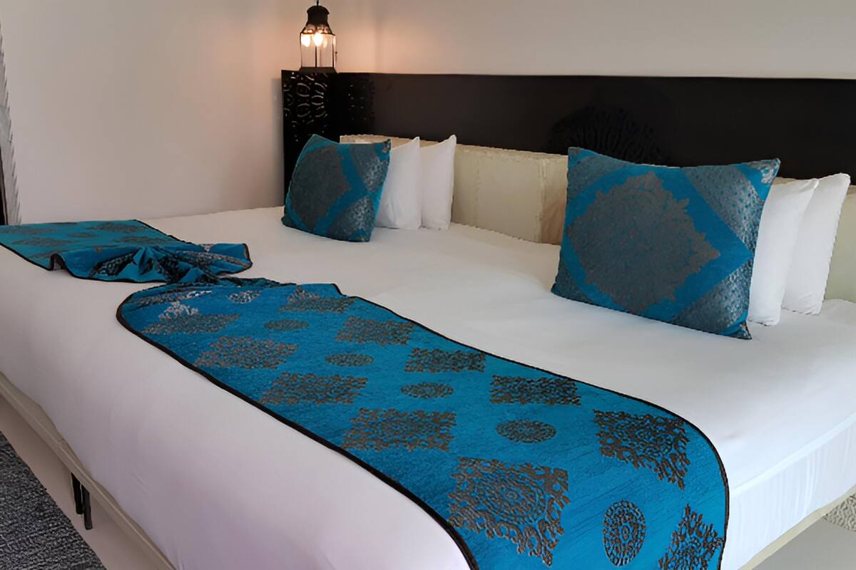 Une chambre d’hôtel avec un grand lit, une tête de lit et une table de chevet avec une lampe.