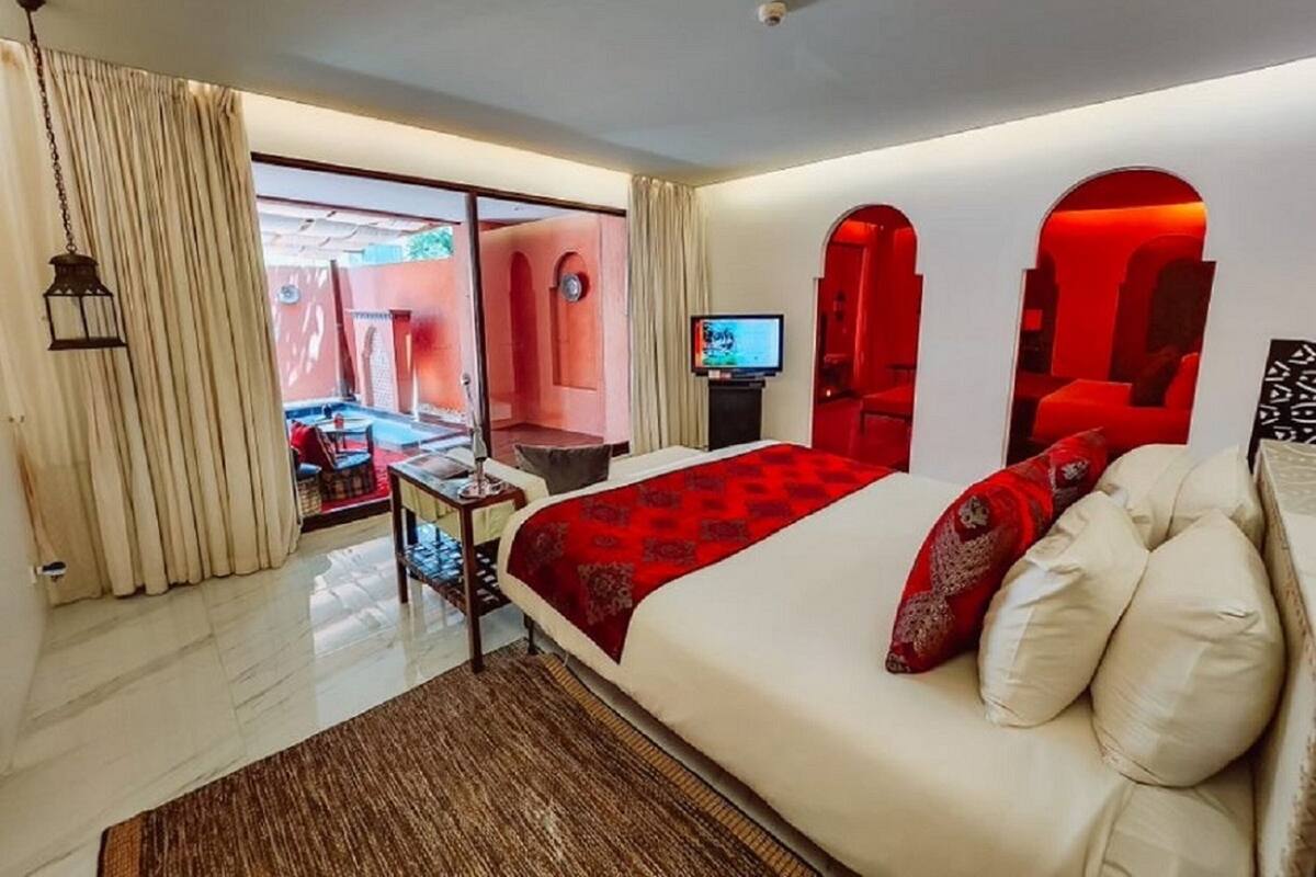 Une chambre d’hôtel moderne dotée d’un grand lit, d’une télévision et donnant sur un espace extérieur.