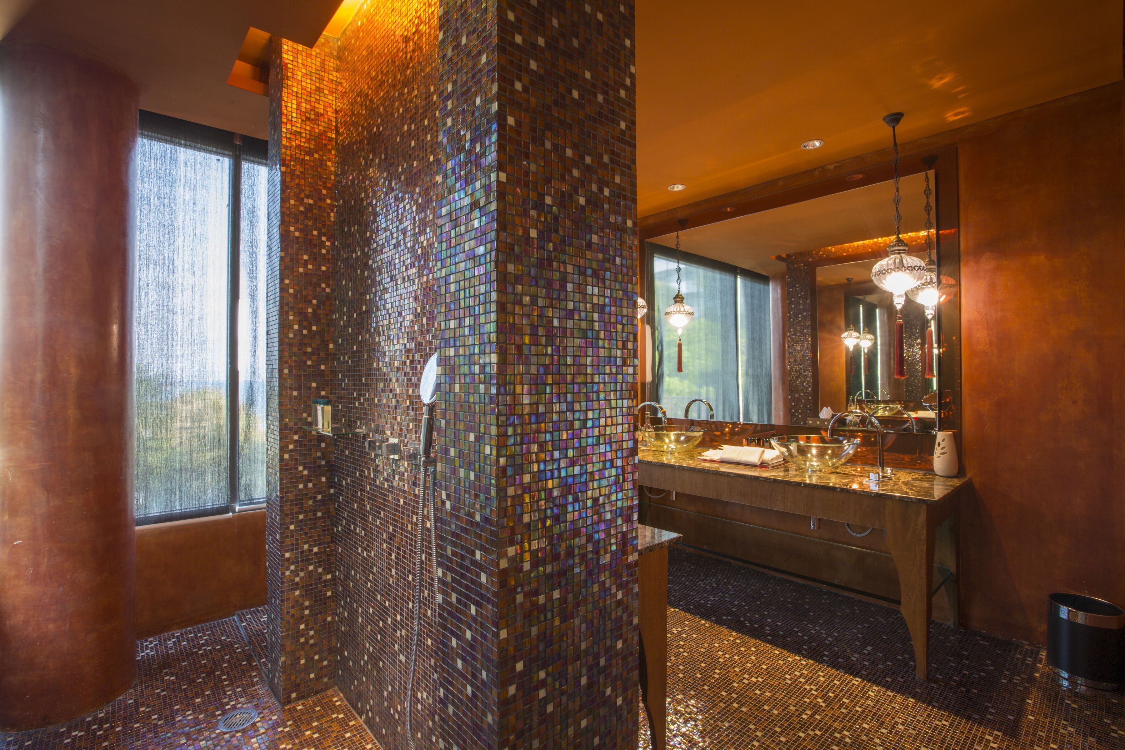 Un baño moderno con pared de mosaicos, un espejo grande y un tocador doble.