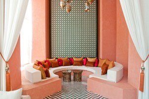 Una sala de estar moderna con un sofá blanco curvo, un muro estampado y faroles decorativos.