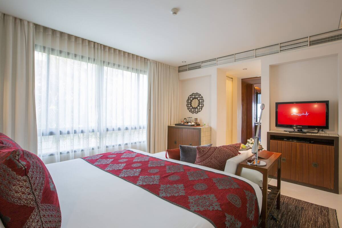 Une chambre d’hôtel avec un grand lit, un bureau, une télévision et une vue sur l’extérieur par la fenêtre.