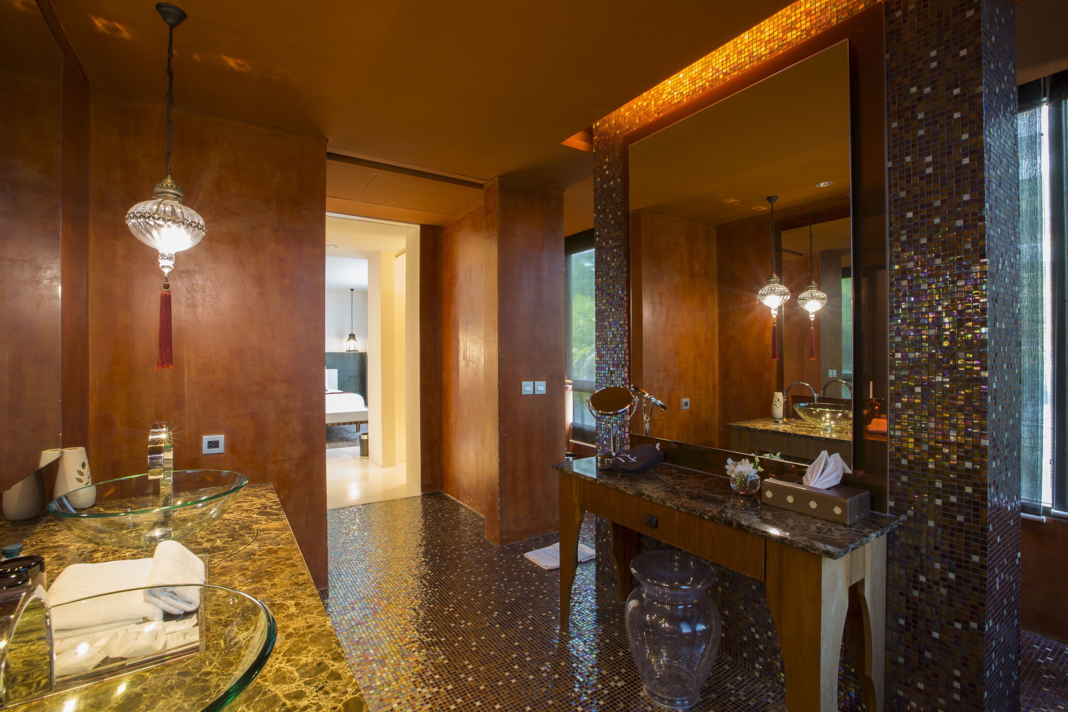 A modern bathroom with a glass bowl sink, a large mirror, and a mosaic tile floor.