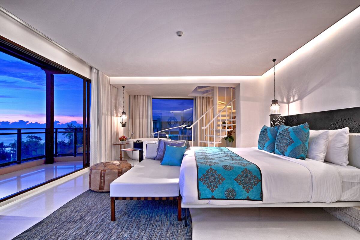 Une chambre moderne avec un grand lit, un canapé et une vue sur l’océan.